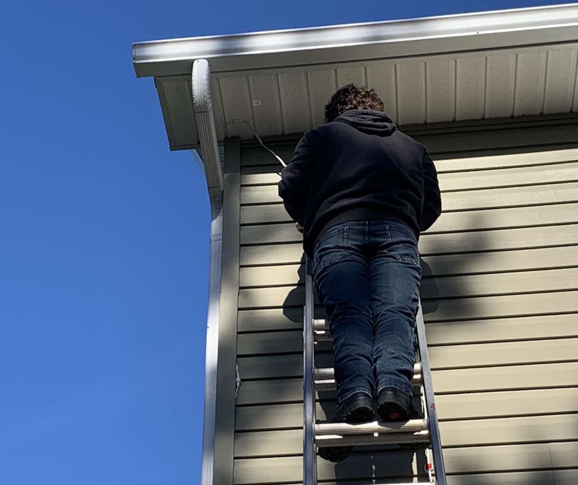 Wash Wizards installer on a ladder fixing lights under the eaves
