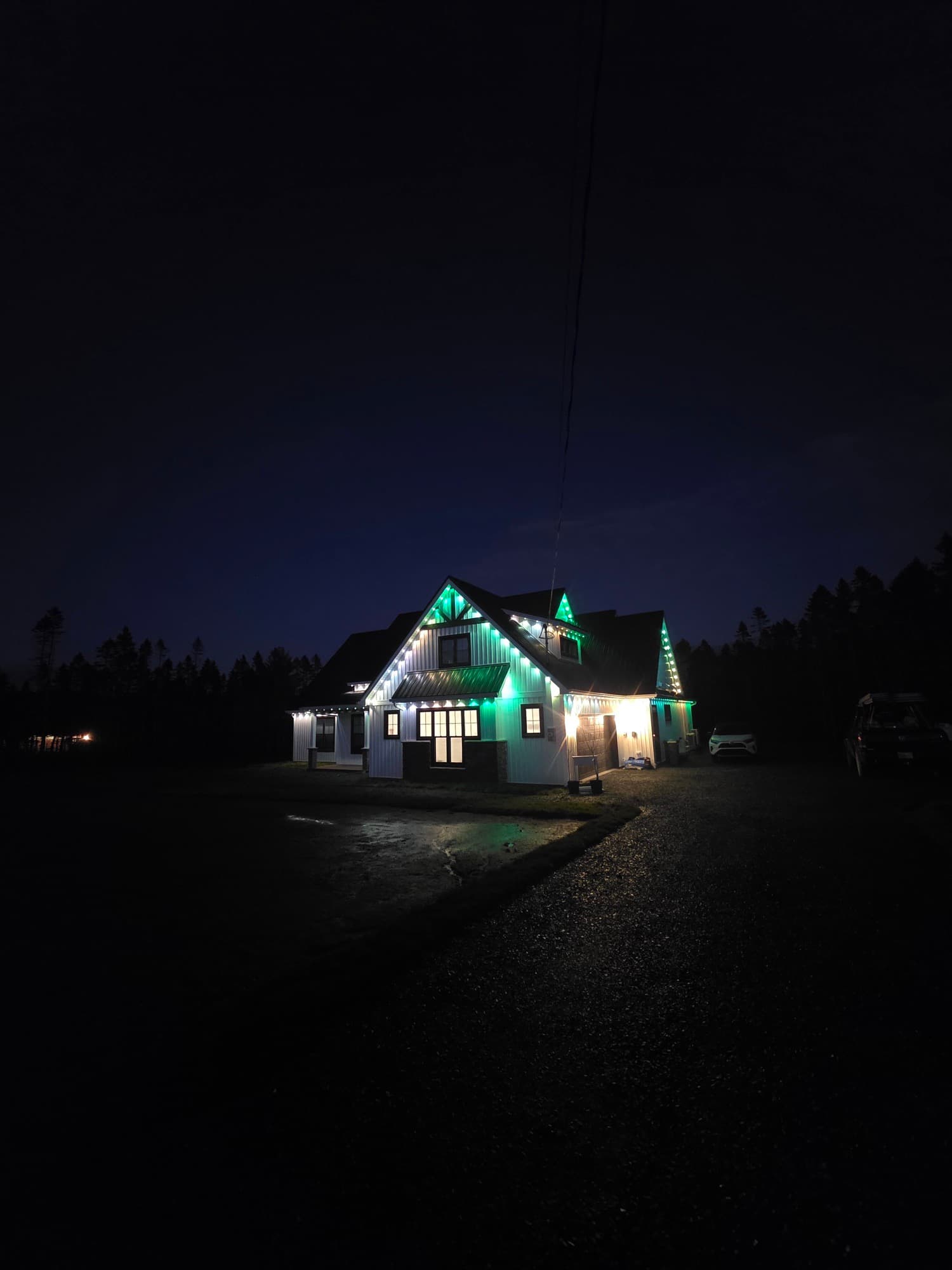 Two-storey farmhouse lit in green along the roofline and gables