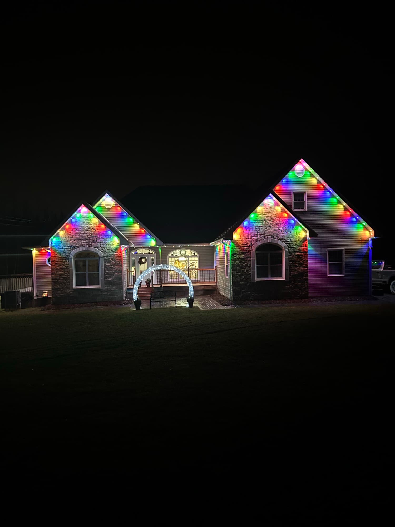 Stone-front home with multicolour roofline lights and a lit archway