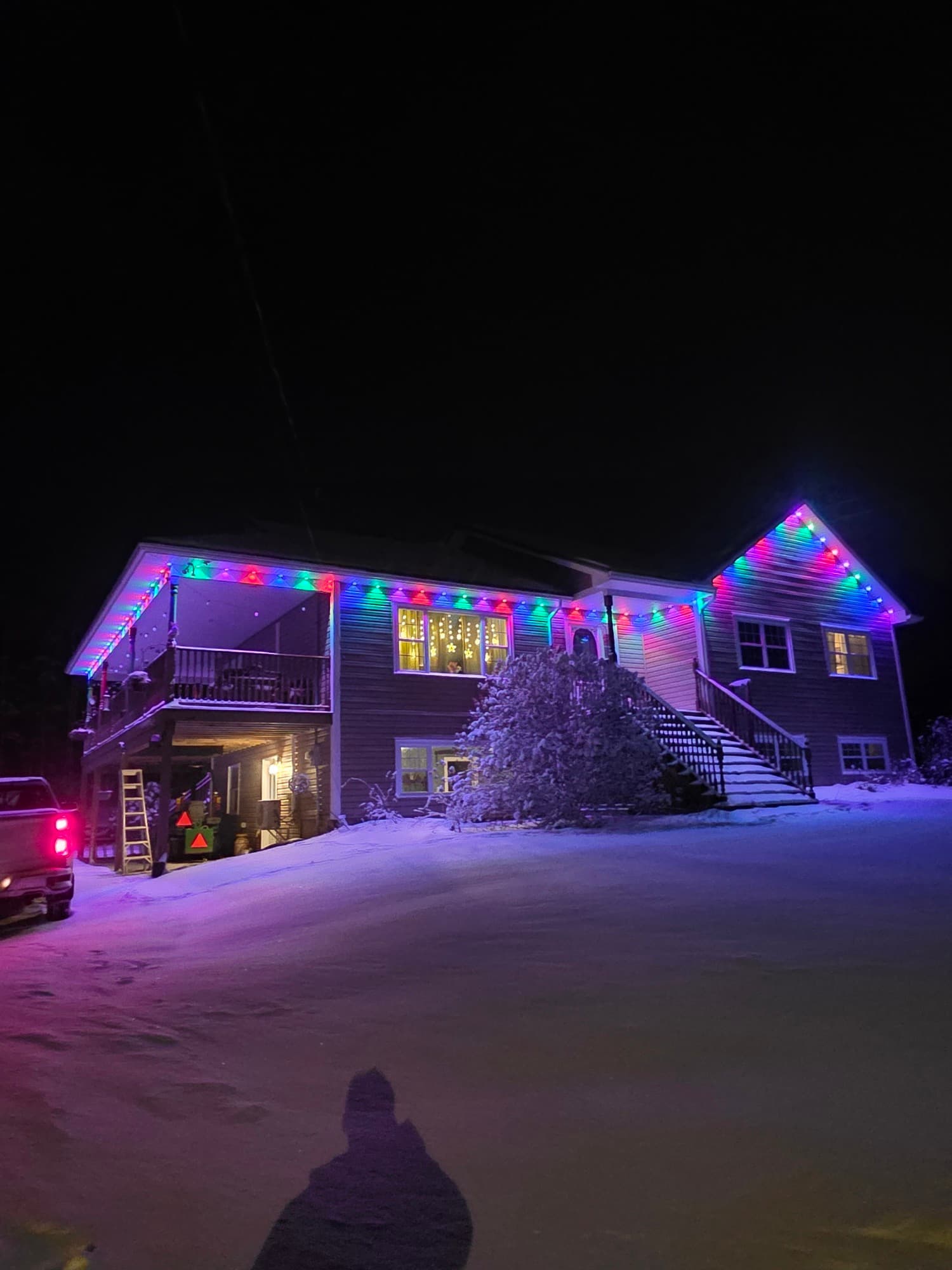 Home outlined in multicolour holiday lights after a snowfall