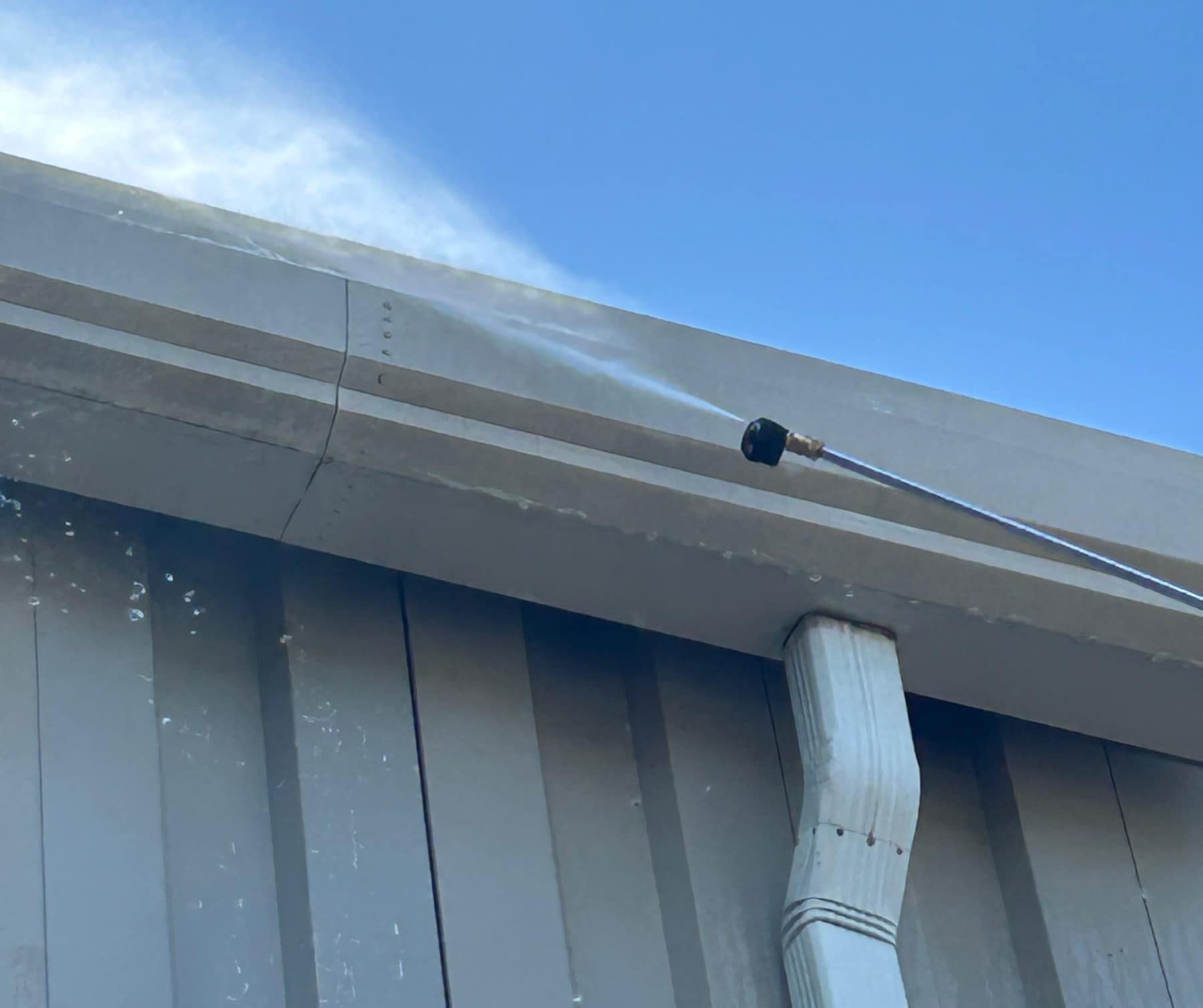 The outside of a gutter and downspout being washed