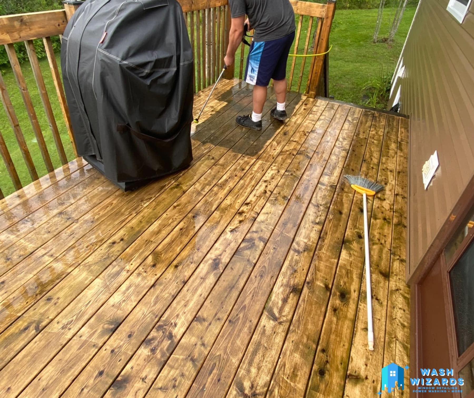 A wooden deck half power washed, the clean boards bright against the grey