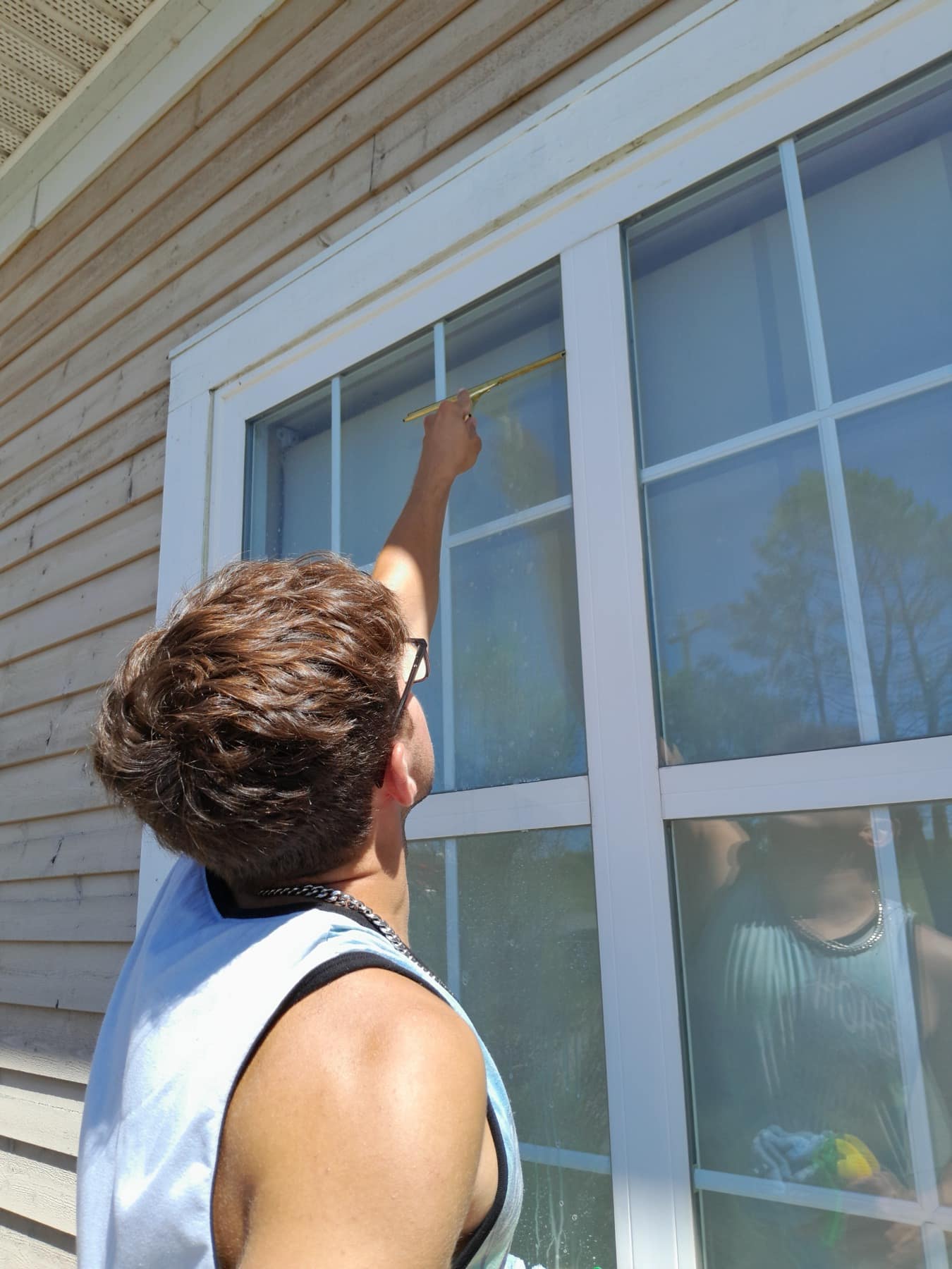 A Wash Wizards crew member squeegeeing a large window on a house